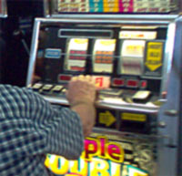 A man playing a slot machine in a gaming 

area.